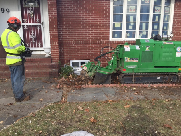 a man is standing next to a green machine in front of a brick house.