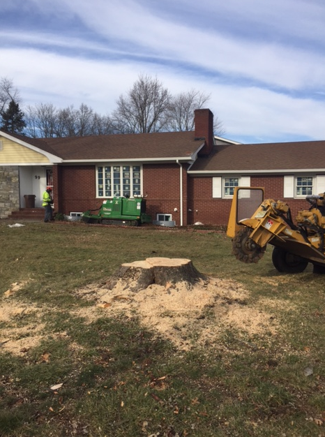 a stump grinder is in front of a brick house.