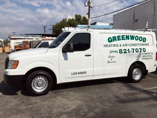 A greenwood heating and air conditioning van is parked in a parking lot