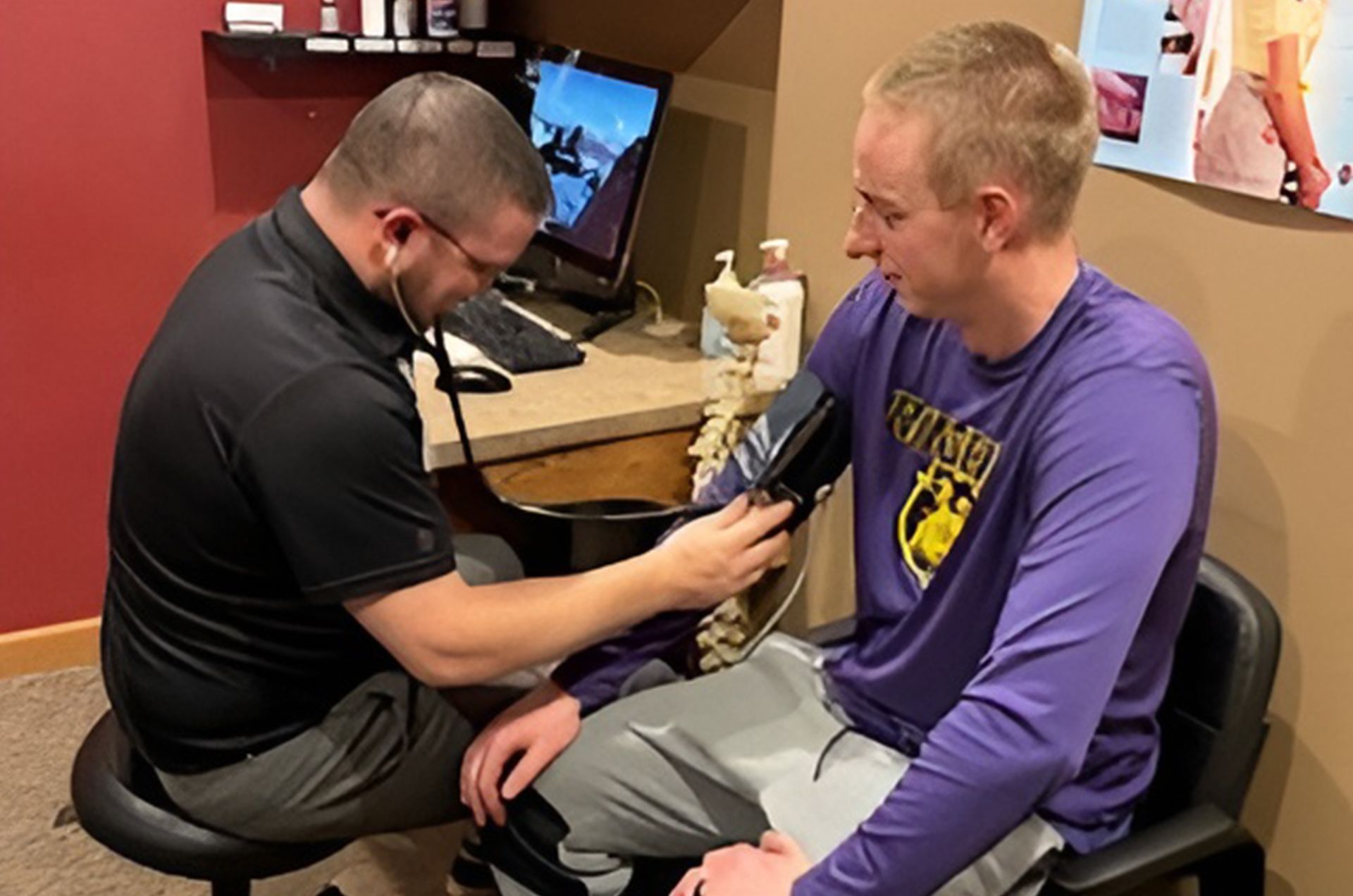 Man having blood pressure taken by a person in a medical setting, using a stethoscope and cuff.