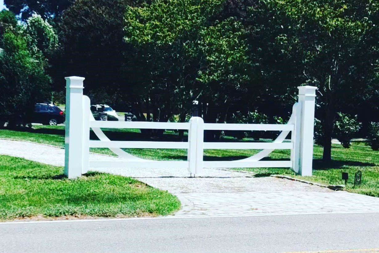 Learn More About Our Powder Coating Services a white gate is open to a driveway with trees in the background