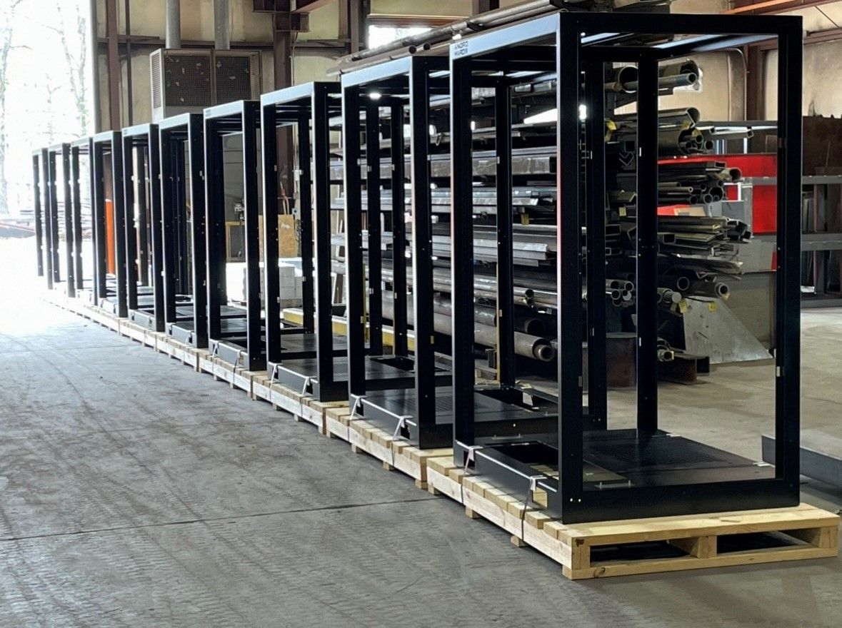 A row of metal frames are sitting on wooden pallets in a warehouse.