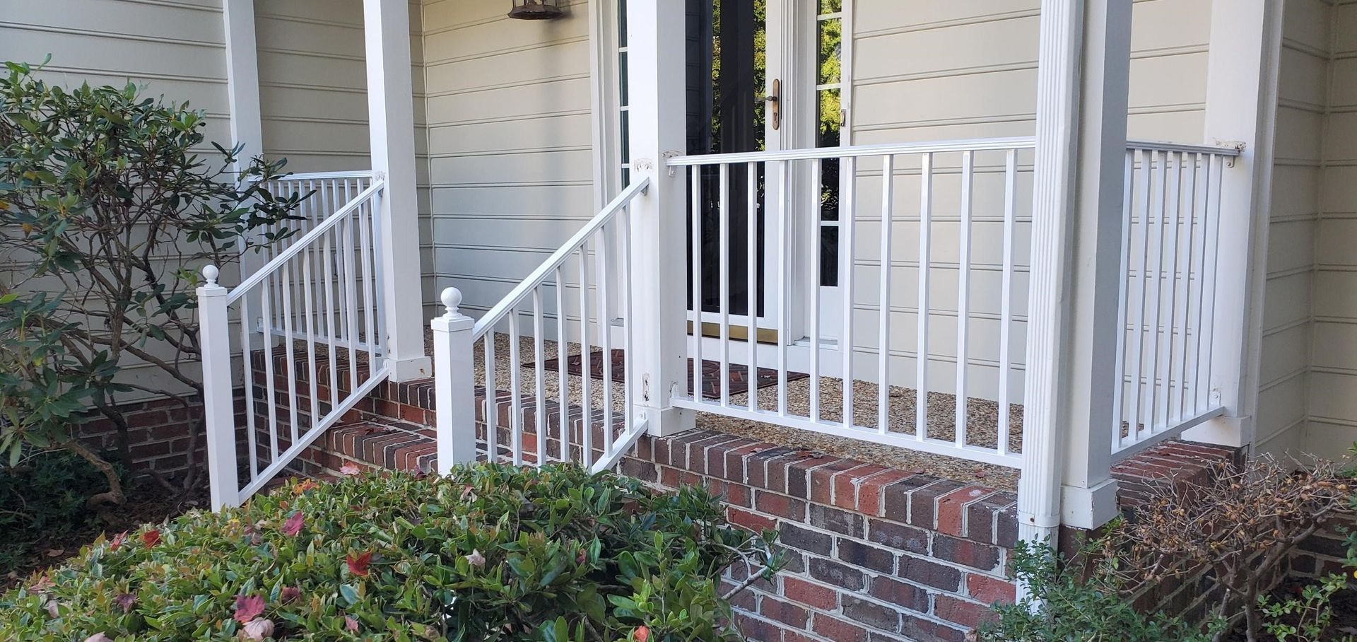 a white porch with a white railing and stairs leading to the front door of a house