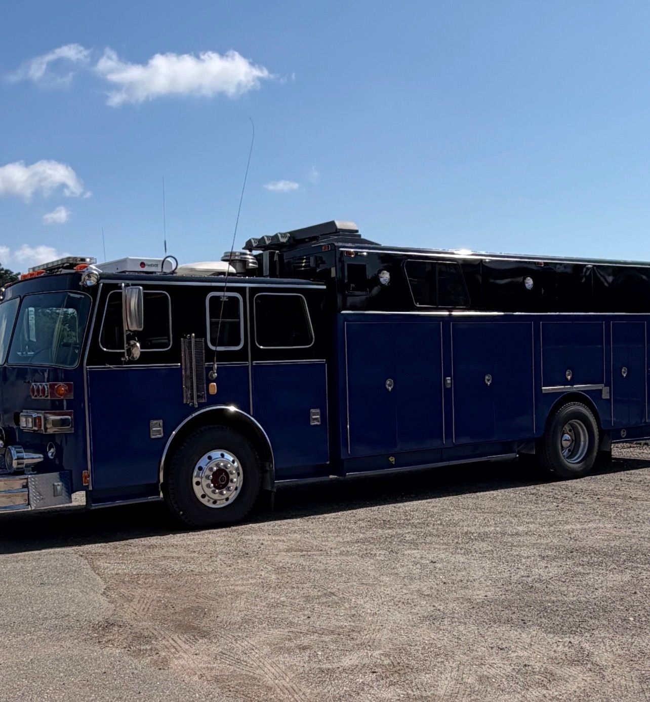 Blue fire truck parked on gravel under a clear sky