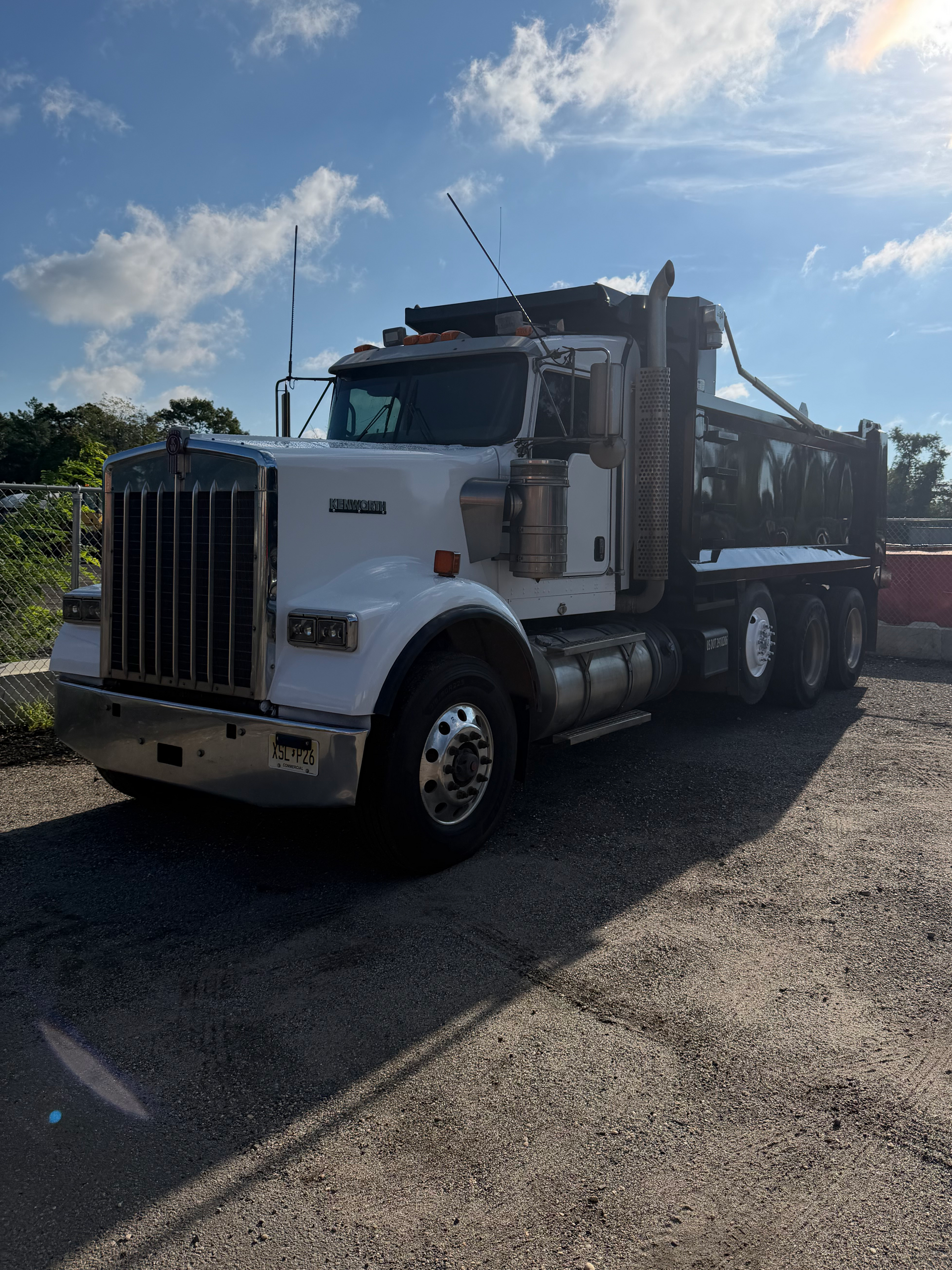 White dump truck parked on a gravel lot under a blue sky