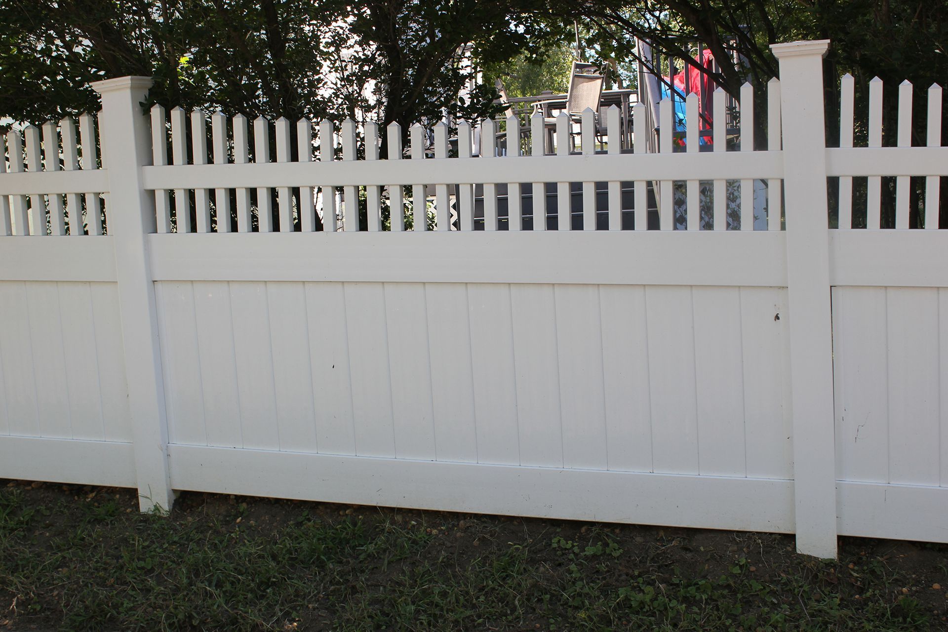 A white fence with a few trees in the background