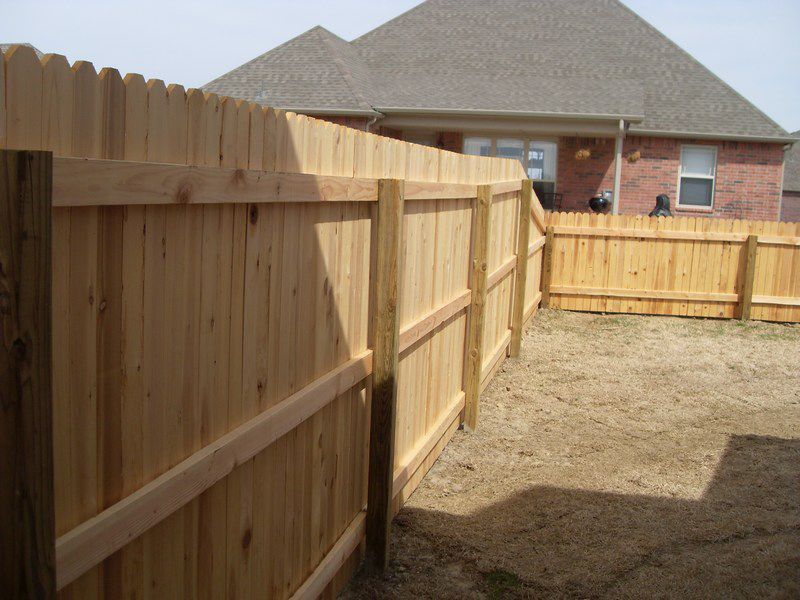 A wooden fence in front of a brick house