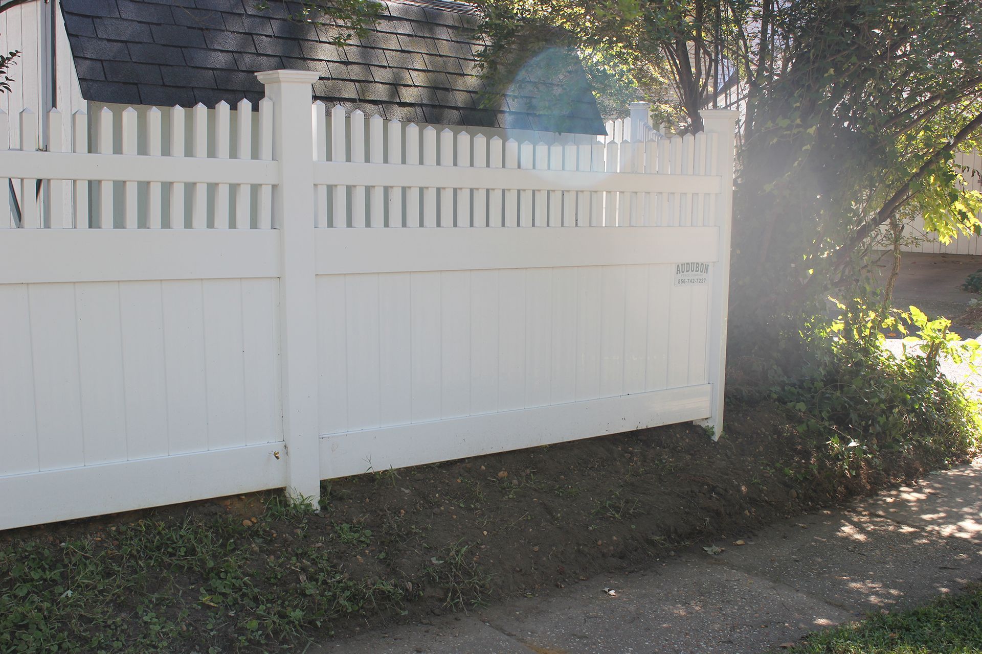 A white picket fence is sitting next to a sidewalk in front of a house.
