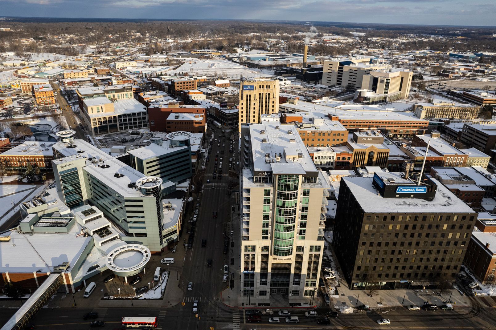 Aerial view of a snowy downtown with tall buildings and a central street stretching into the distance