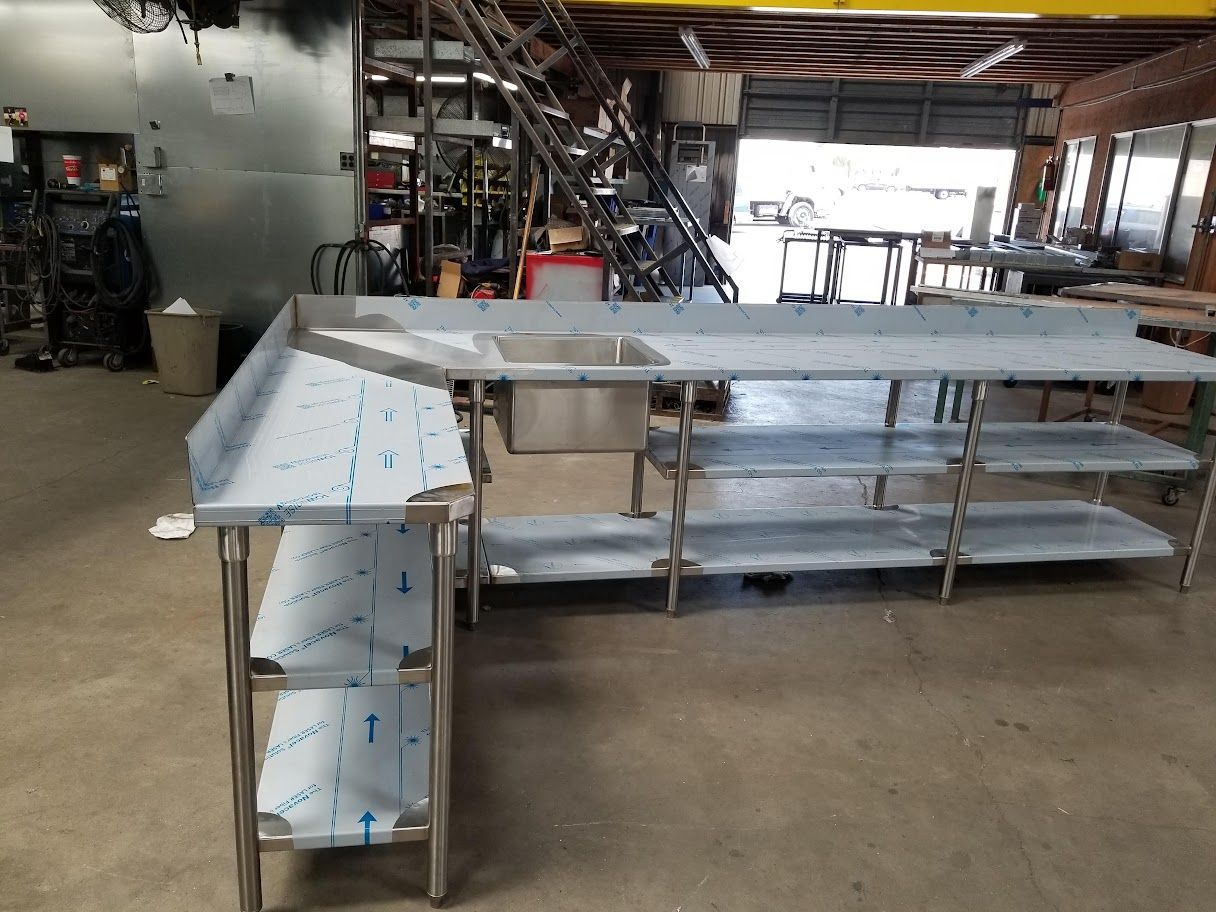 A stainless steel table with shelves and a sink in a factory.