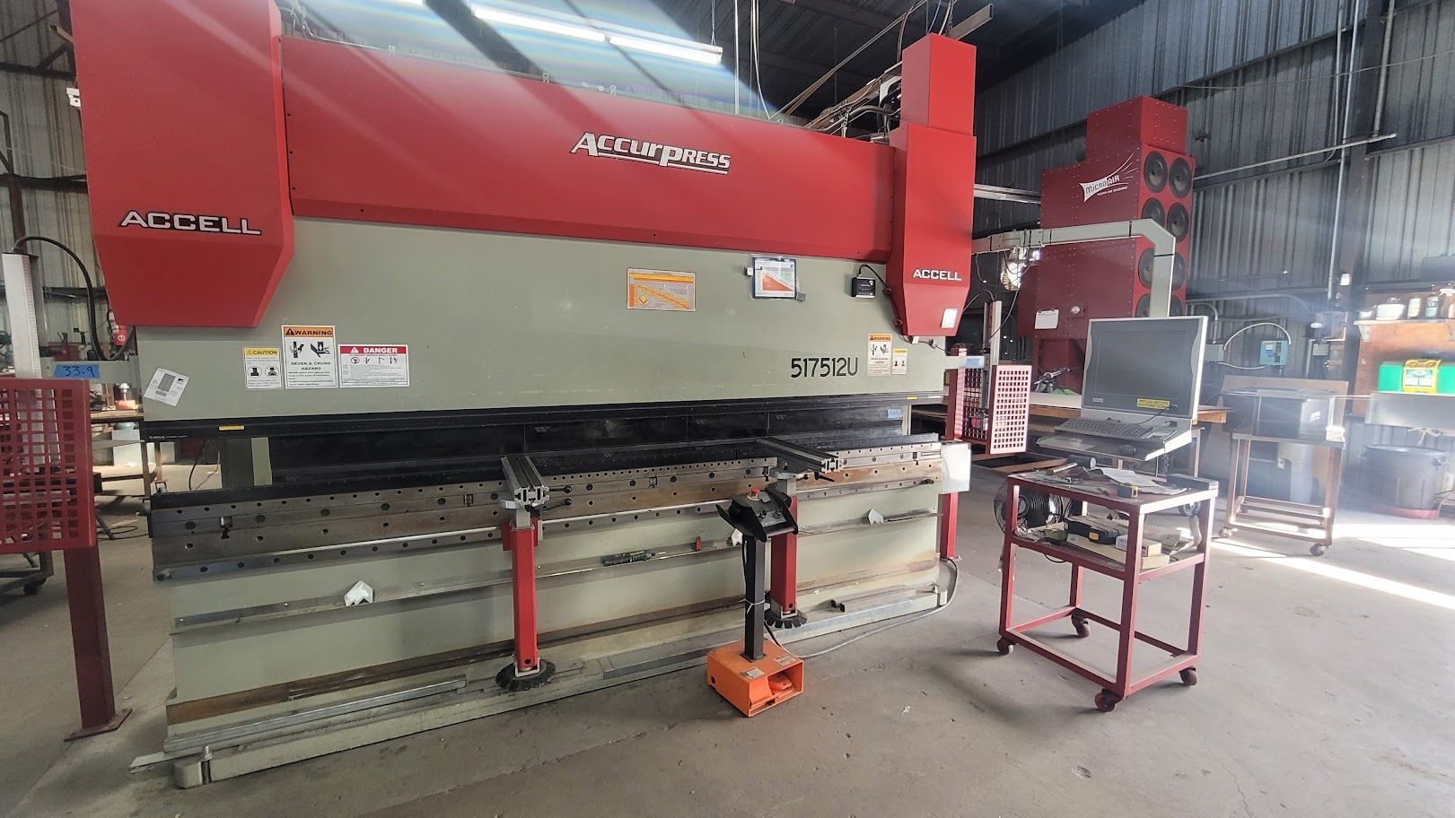 A machine is sitting in a warehouse next to a cart.