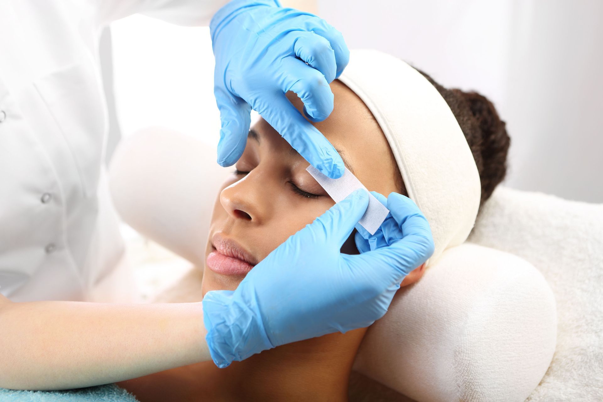 A woman is getting a wax treatment on her face.