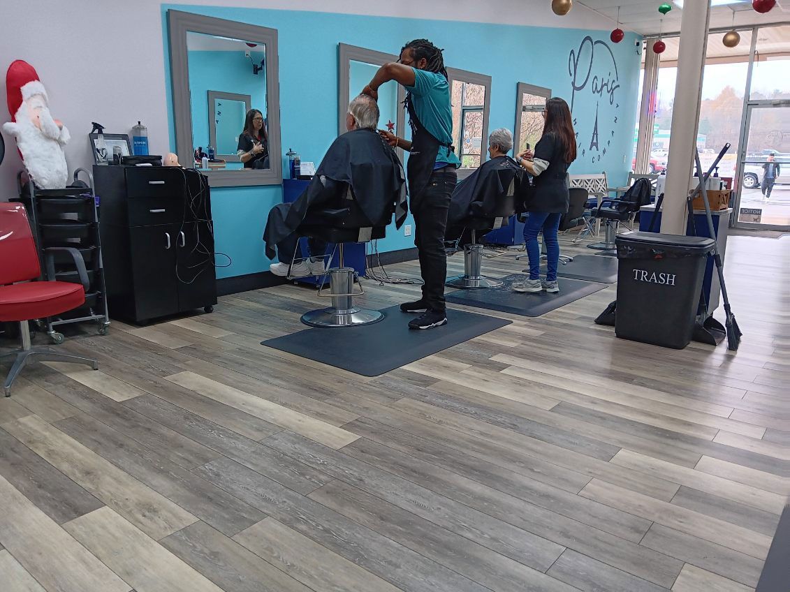 A woman is cutting a man 's hair in a hair salon.