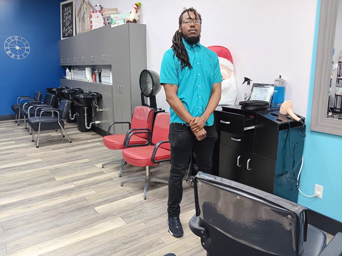 A man is standing in a hair salon next to a chair