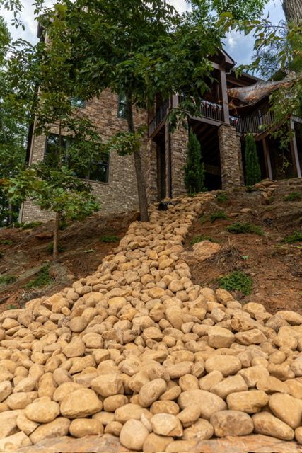 Stone path leading to a rustic house nestled among trees on a hillside
