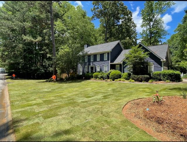 Suburban house with manicured lawn, trees, and bright blue sky on a sunny day