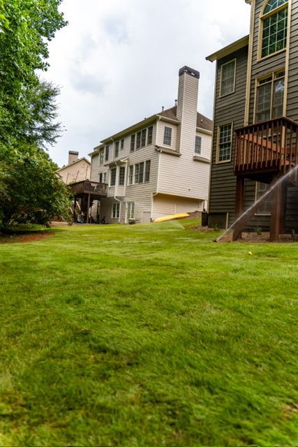 Apartment buildings with white siding beside a green grassy courtyard and trees