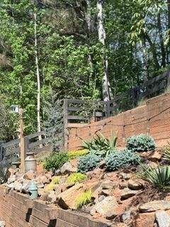 Stone retaining wall with succulents and trees in a sloped garden.
