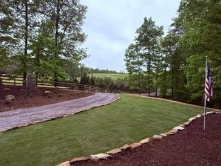 Curved stone path beside a green lawn, framed by trees, with an American flag on the right.