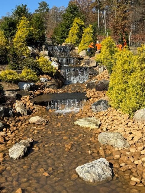 Tiered waterfall over rocky stream bed with autumn trees and yellow-green foliage