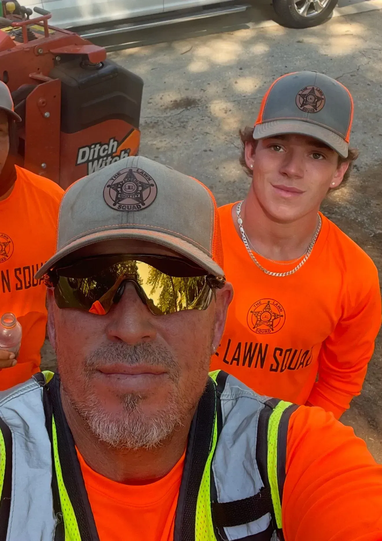 Three people in orange shirts and caps, with 