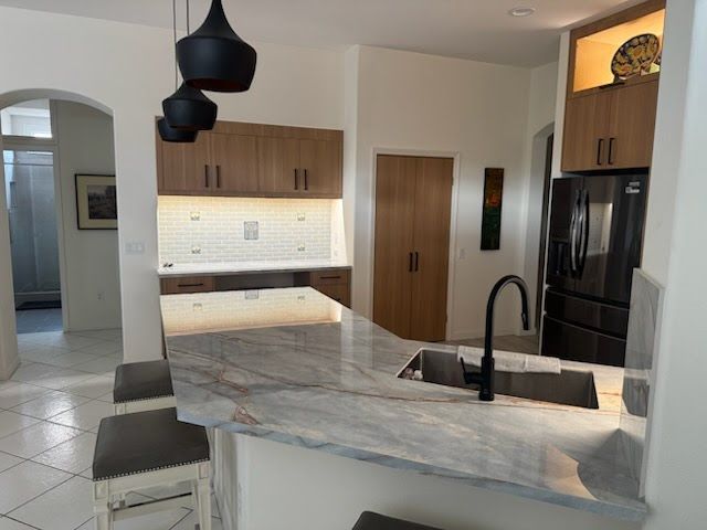 Modern kitchen with brown cabinets, white countertop, black fixtures, and pendant lights.