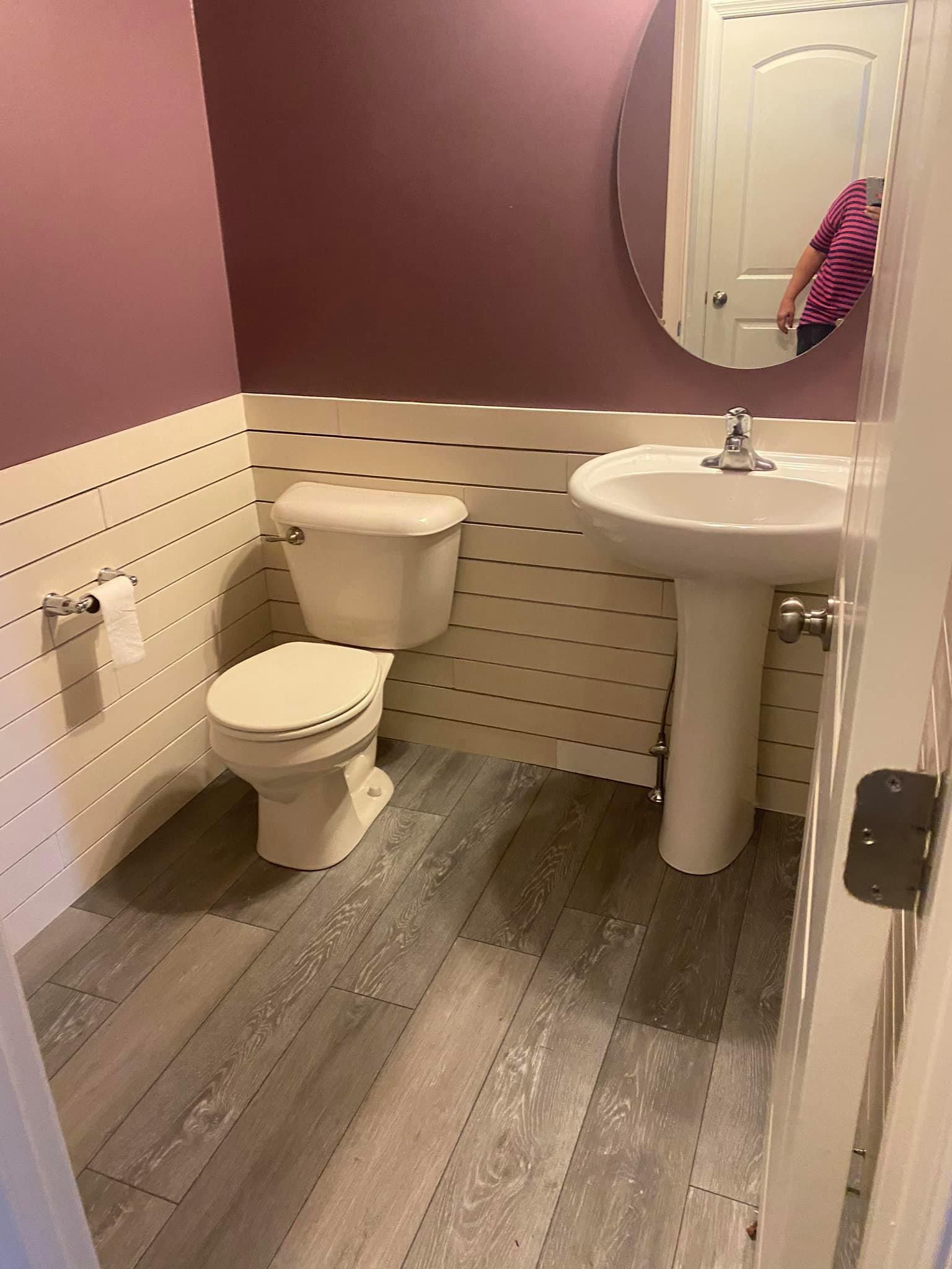 an after picture of a bathroom with a toilet, sink, and mirror