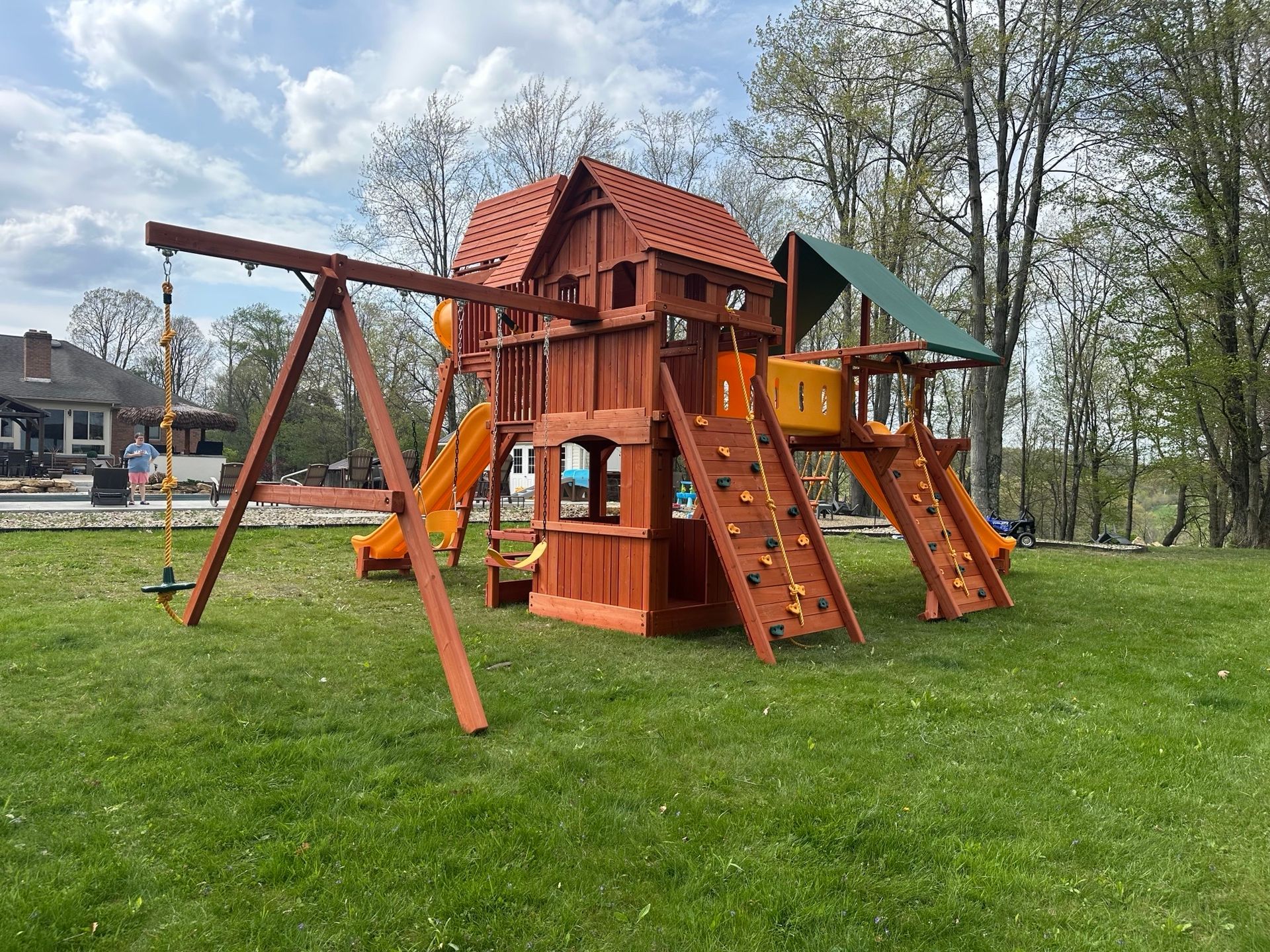 Wooden playground tower with slides and swings on a grassy park lawn