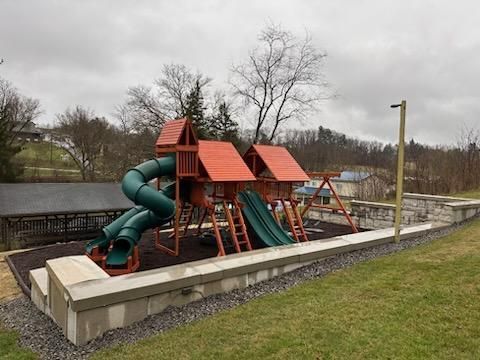 Playground with red-roofed slides and green tube slides beside a lake on an overcast day