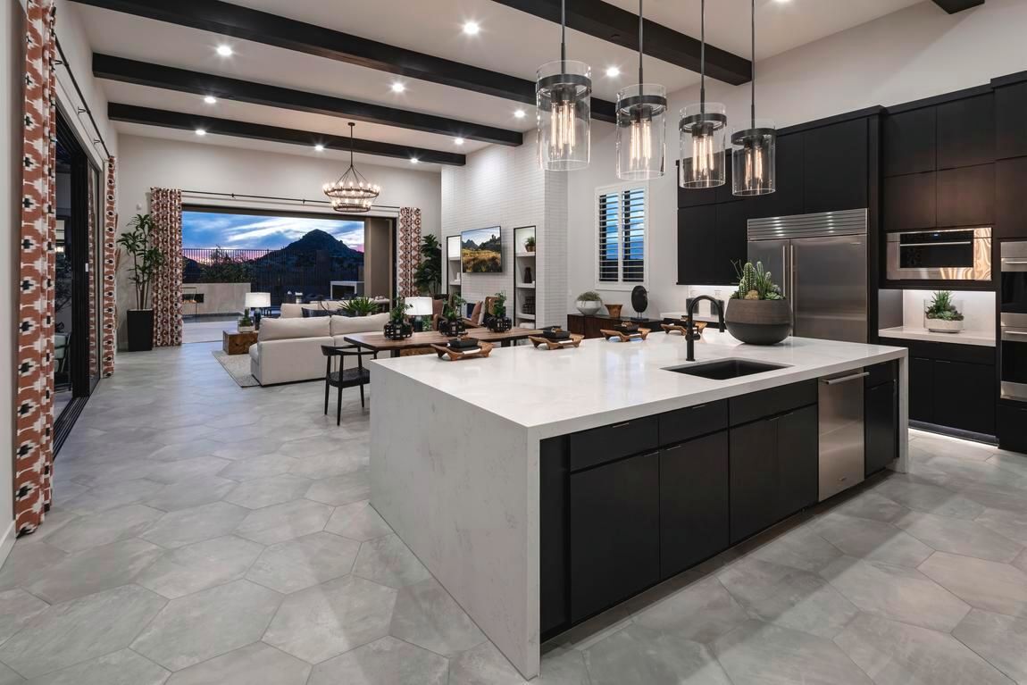 Modern kitchen with island, black cabinets, open to living area, sliding glass door.