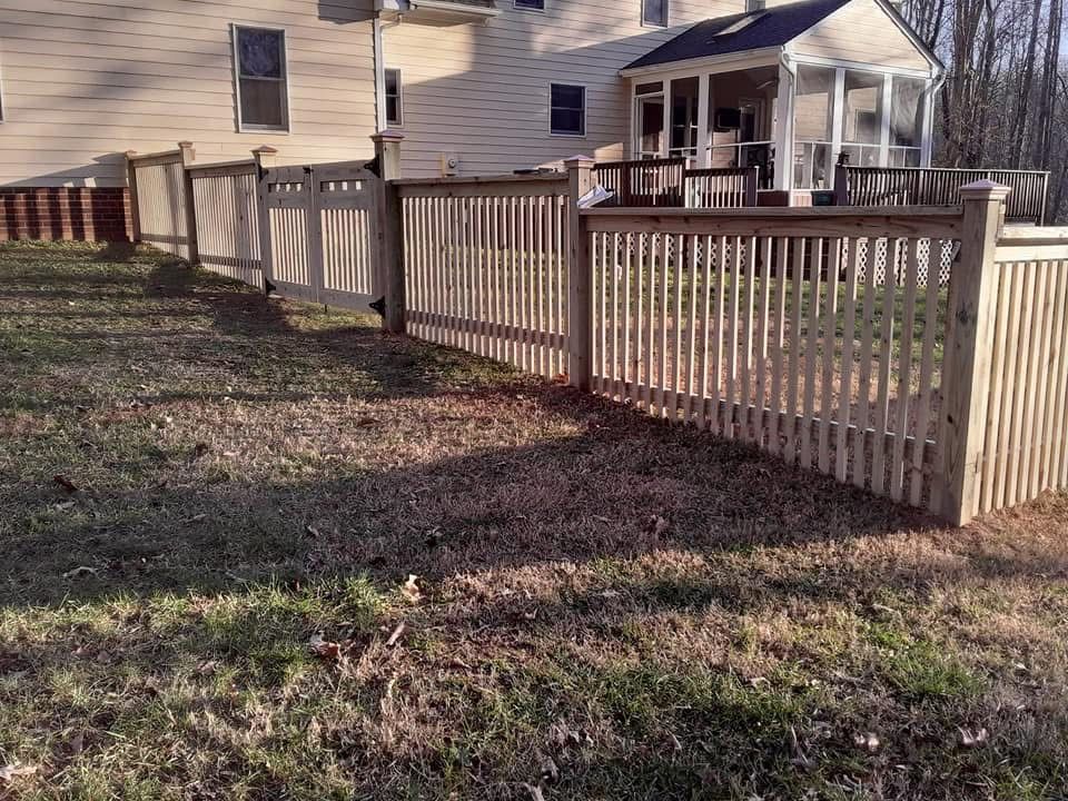 A wooden fence surrounds a yard in front of a house.