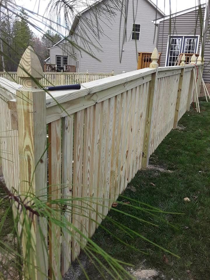 A wooden fence is sitting in the grass in front of a house.