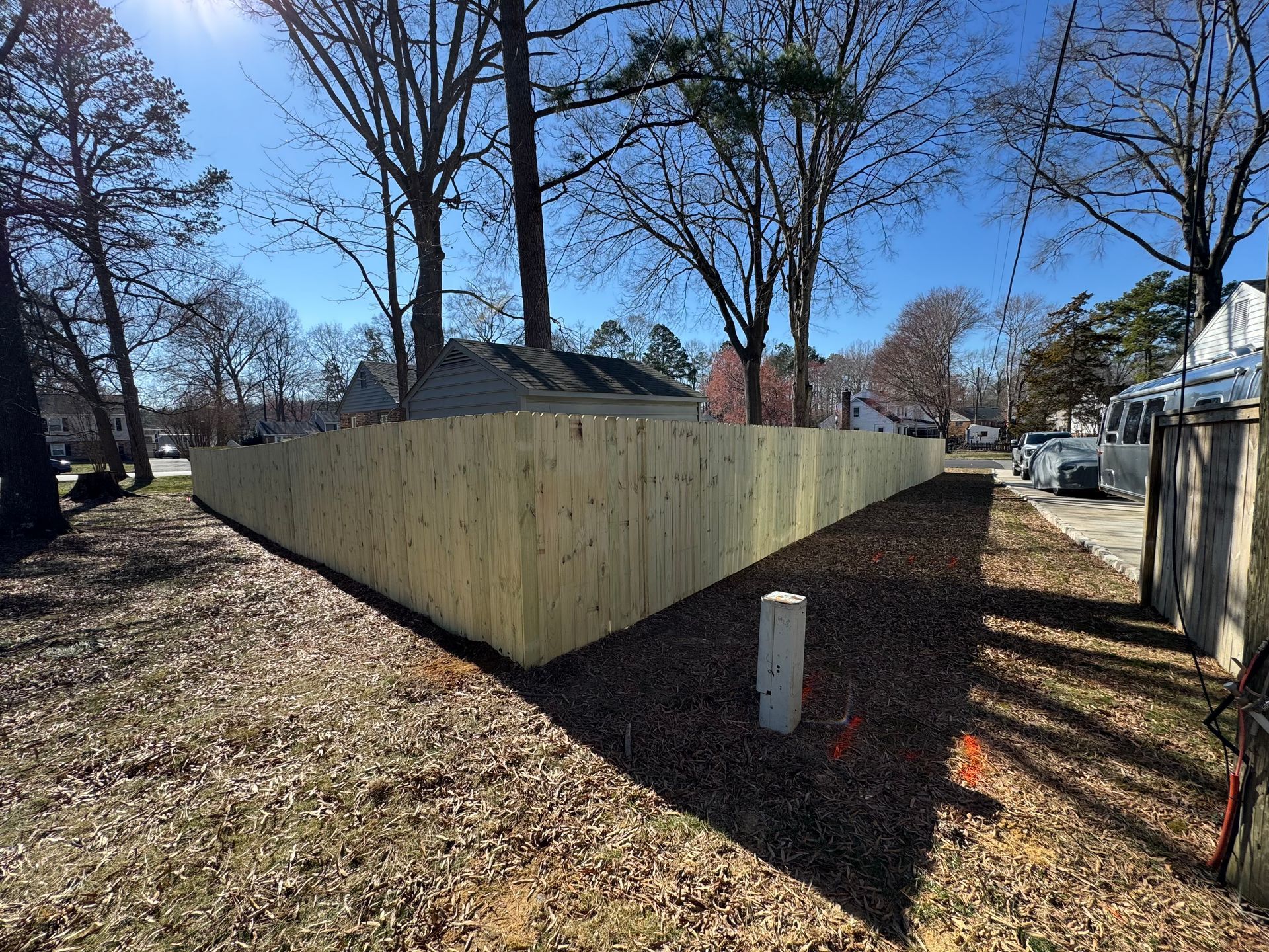A wooden fence is surrounded by trees in a yard.