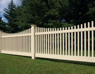 A white picket fence is sitting in the middle of a lush green field.