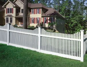 A white picket fence is in front of a large house.
