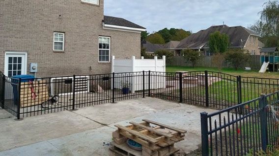 A backyard with a fence and a pallet in front of a house.