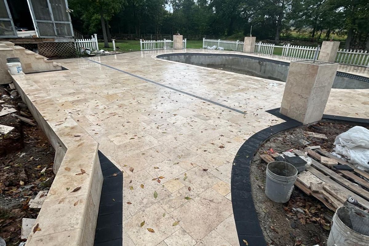 A patio with a swimming pool in the background is being built.