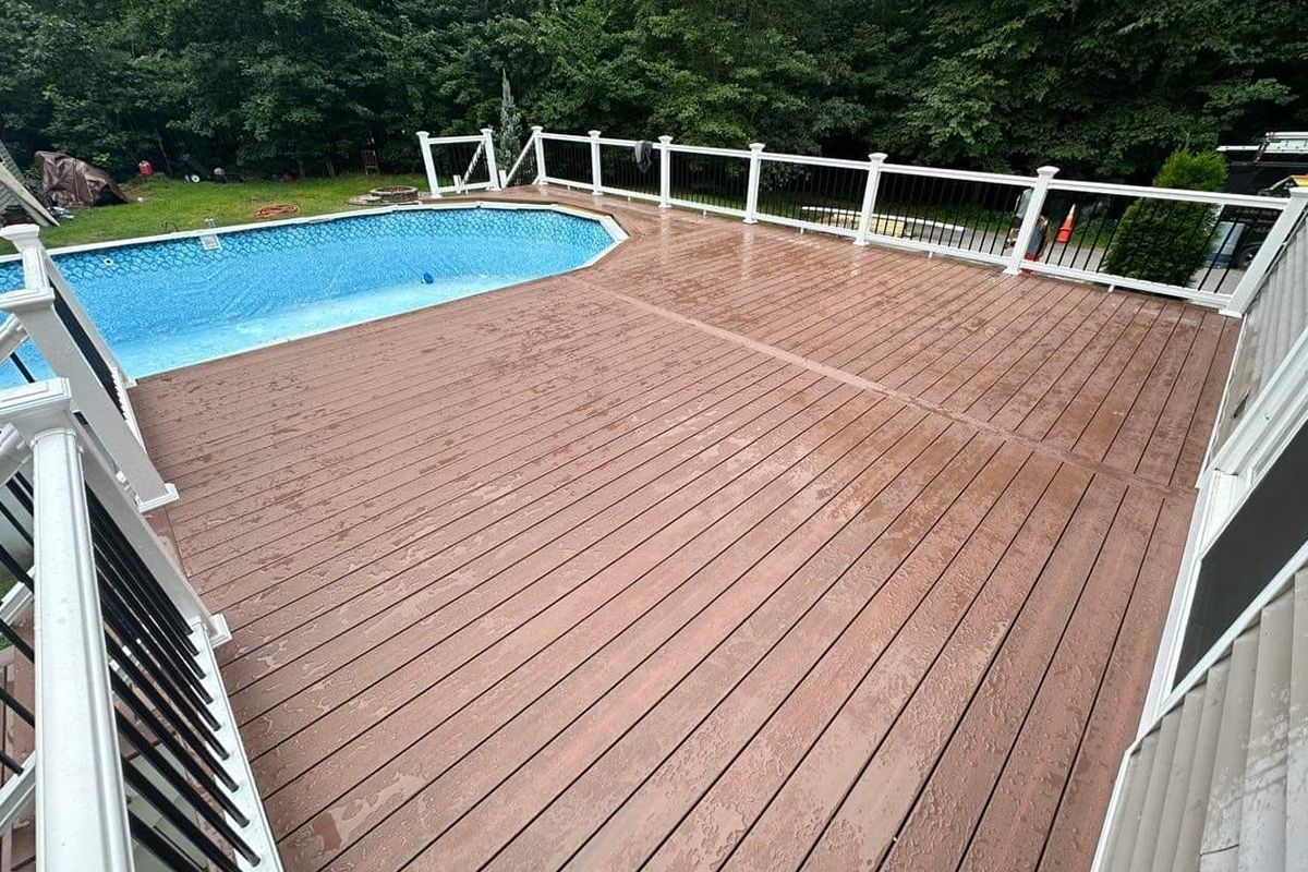 A large wooden deck with a swimming pool in the background.