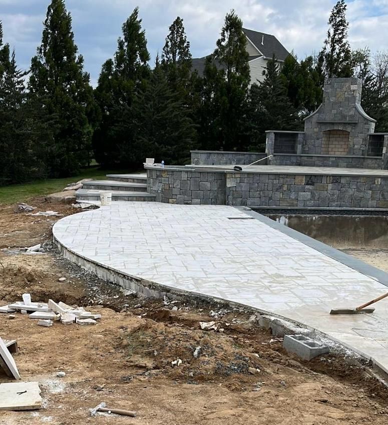 A concrete walkway is being built around a swimming pool