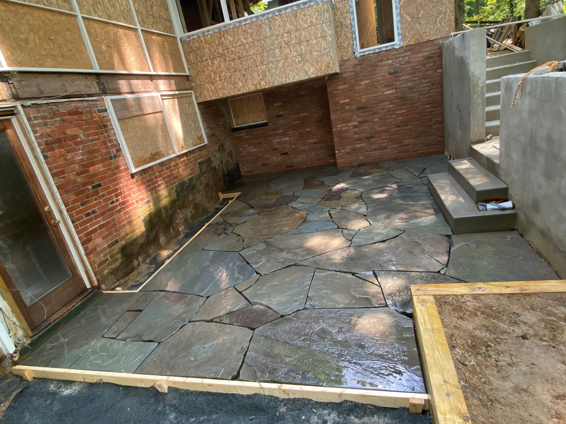 A stone patio is being built in the backyard of a house.