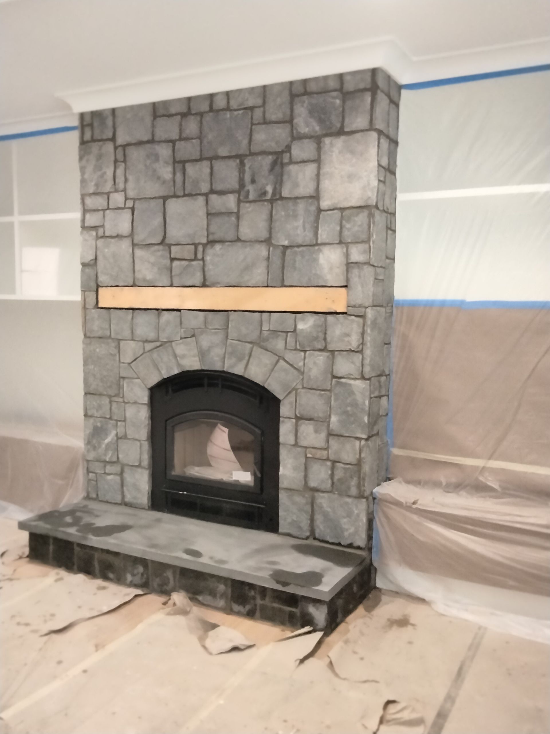 A stone fireplace is being painted in a room