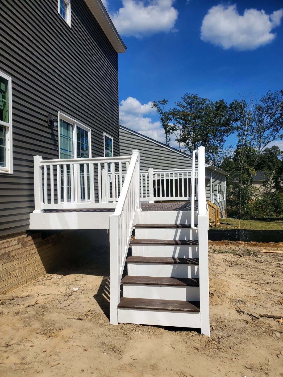 A deck with stairs leading up to it and a house in the background