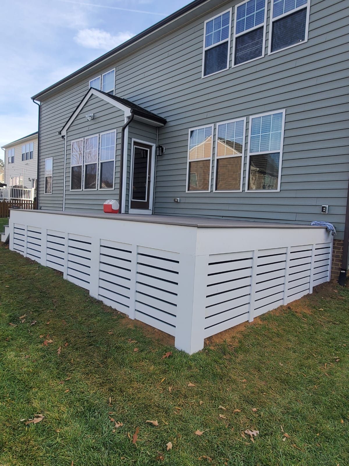 A house with a large deck and a white fence in front of it.
