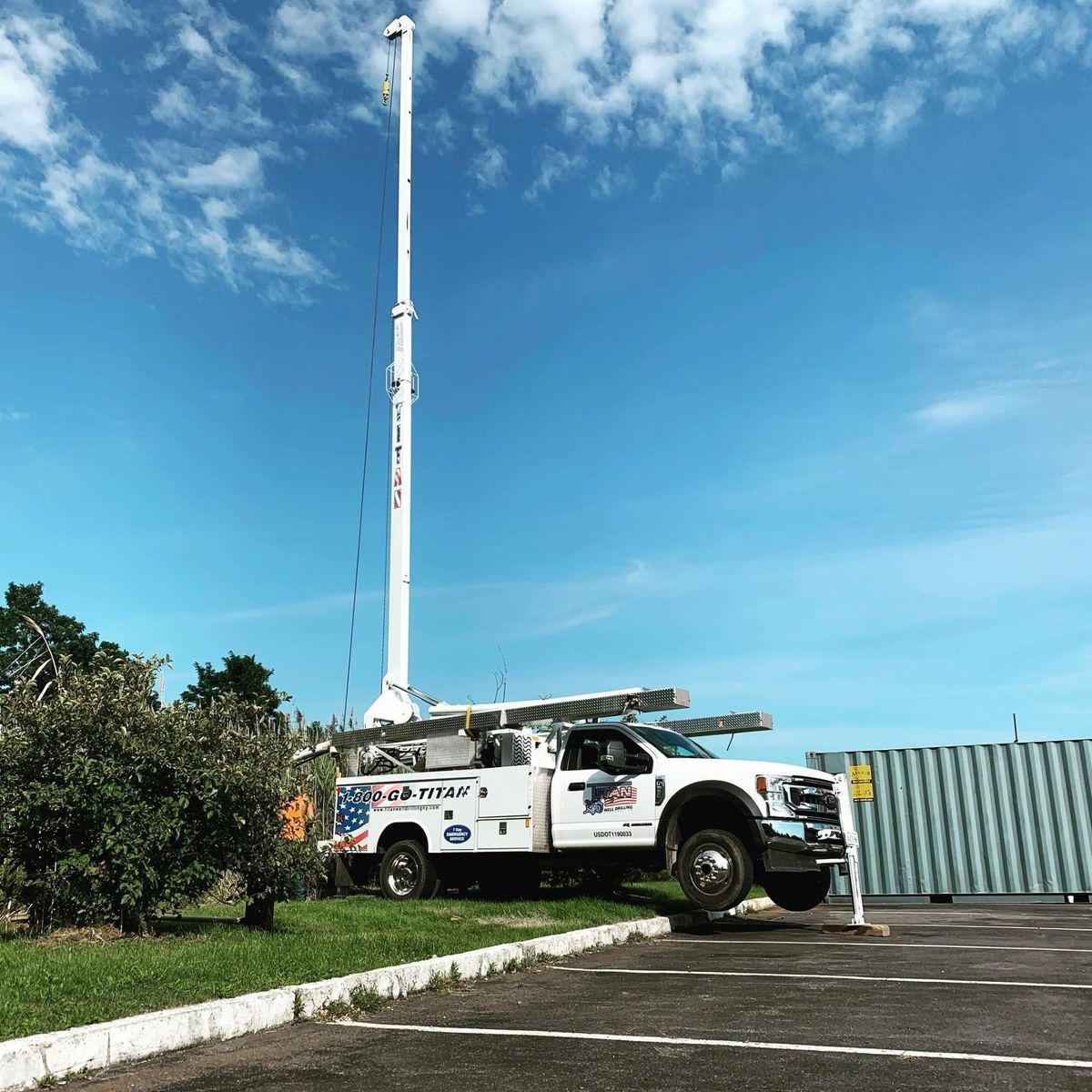 White utility truck with an extended boom under a blue sky.