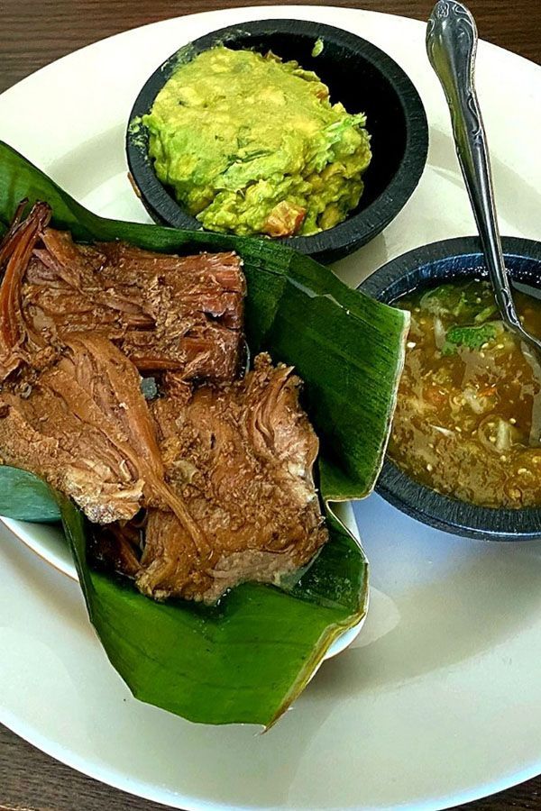 A white plate topped with meat , guacamole and sauce.