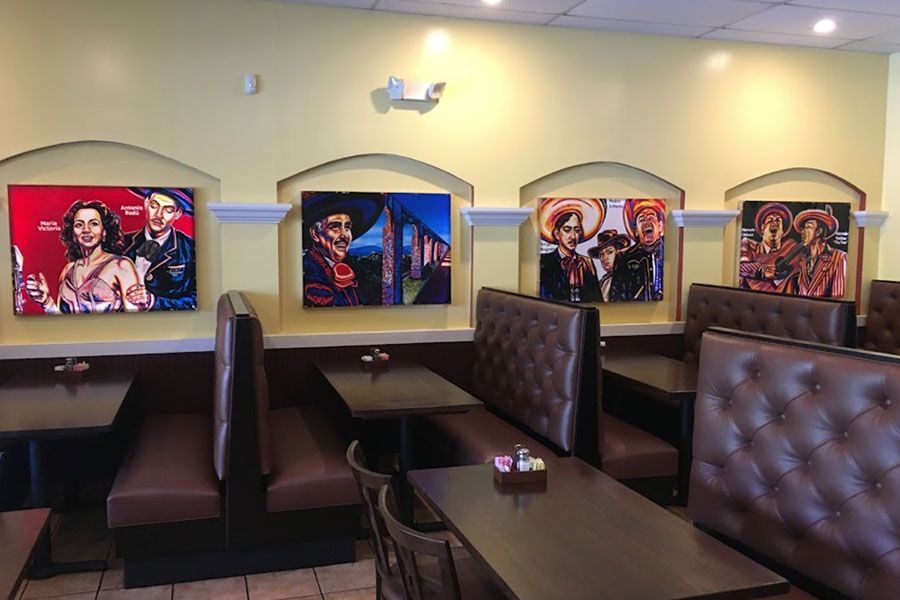 A restaurant with tables and benches and paintings on the wall.