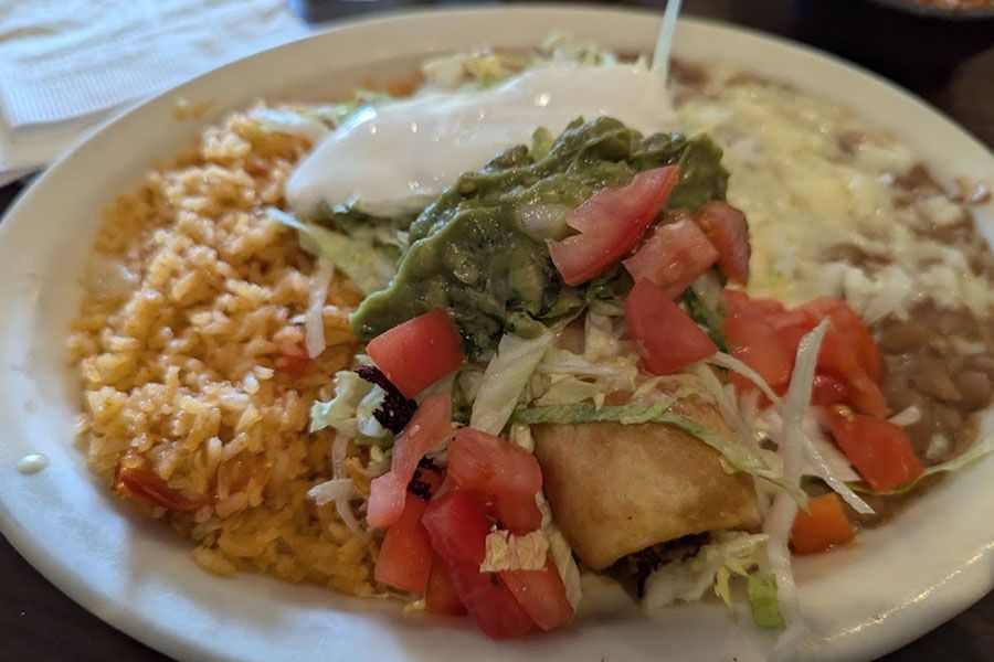 A plate of mexican food with rice , beans , guacamole and tortillas on a table.