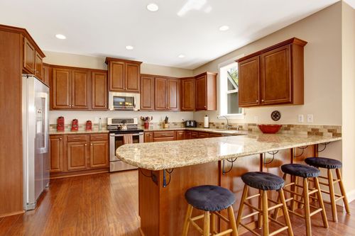 Kitchen with wooden cabinets, granite countertops, stainless steel appliances, and breakfast bar with stools.