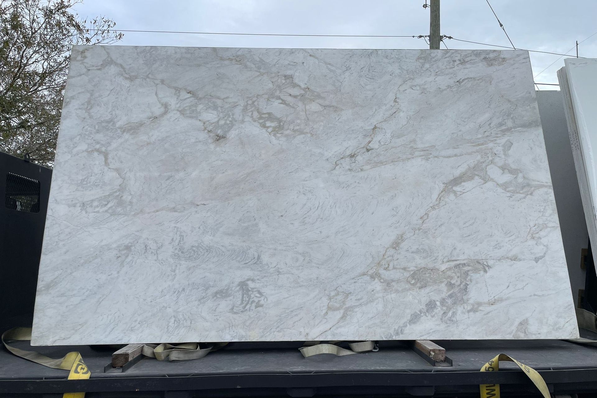 Outdoor kitchen with grill, sink, and countertop. Patio with dining table, chairs, and umbrella. Green grass, brick and black fence.