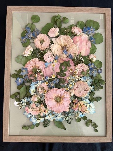 A picture of pink and blue flowers in a wooden frame